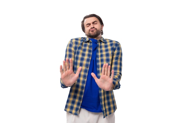 Jonge blanke brunette man met een baard en een oorbel is gekleed in een blauw geruite shirt en t-shirt