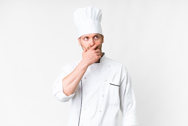 Jonge blanke chef-kok over geïsoleerde witte achtergrond met twijfels en met een verwarde gezichtsuitdrukking