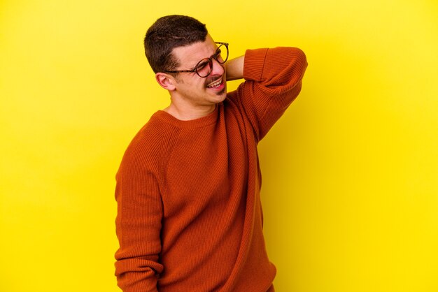 Jonge blanke coole man geïsoleerd op geel met nekpijn als gevolg van een zittende levensstijl.