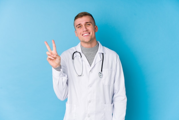 Jonge blanke dokter man blij en zorgeloos met een vredessymbool met vingers