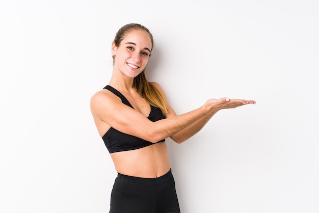 Jonge blanke fitness vrouw poseren op een witte achtergrond met een kopie ruimte op een palm.