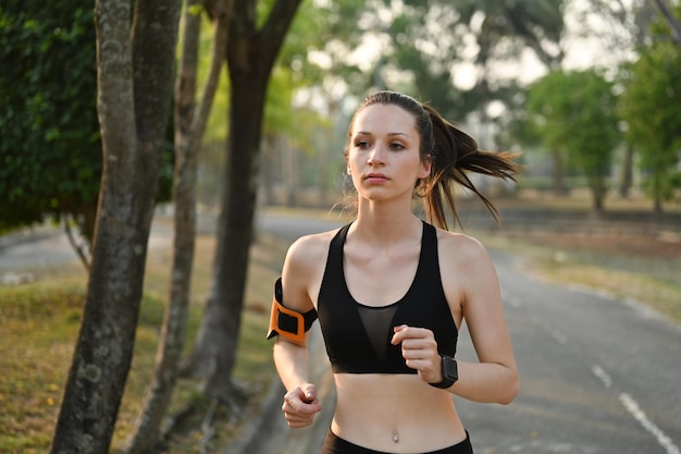 Jonge blanke fitnessvrouw die op zonnige zomerdag in het park loopt Fitnesstraining en gezond levensstijlconcept
