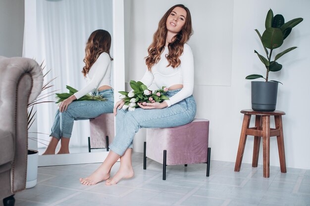 Jonge blanke gelukkige vrouw ruikend boeket verse tulpen thuis.