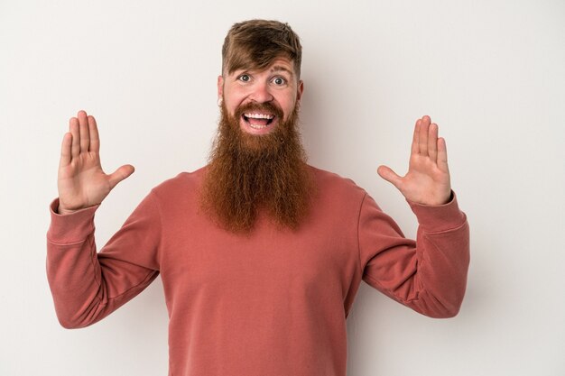 Foto jonge blanke gember man met lange baard geïsoleerd op een witte achtergrond met iets kleins met wijsvingers, glimlachend en zelfverzekerd.