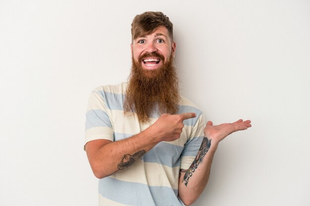 Jonge blanke gember man met lange baard geïsoleerd op een witte achtergrond opgewonden met een kopie ruimte op de palm.