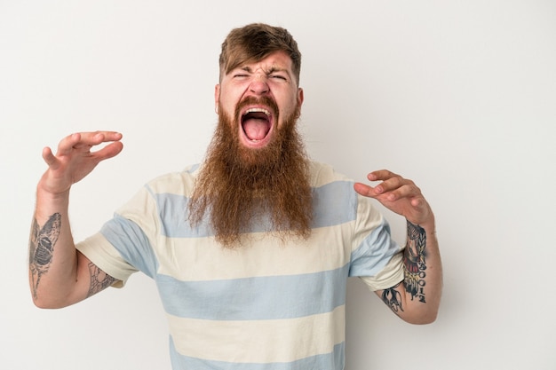 Jonge blanke gember man met lange baard geïsoleerd op een witte achtergrond schreeuwen naar de hemel, opzoeken, gefrustreerd.