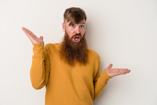 Jonge blanke gember man met lange baard geïsoleerd op een witte achtergrond verward en twijfelachtig schouders ophalen om een kopie ruimte te houden.