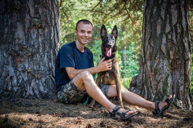 Jonge blanke hipster brengt tijd door met zijn hond in het park op een zonnige zomerdag Het concept van een huisdier als familielid