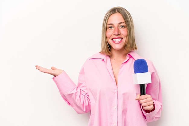 Jonge blanke journaliste vrouw geïsoleerd op een witte achtergrond met een kopie ruimte op een handpalm en met een andere hand op de taille