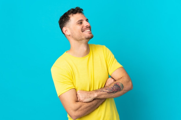 Jonge blanke knappe man geïsoleerd op blauw blij en lachend