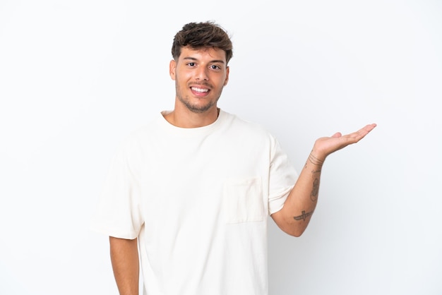 Jonge blanke knappe man geïsoleerd op een witte achtergrond met copyspace denkbeeldig op de palm om een advertentie in te voegen