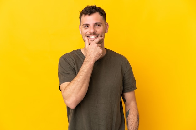 Jonge blanke knappe man geïsoleerd op geel denken