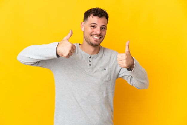 Jonge blanke knappe man geïsoleerd op geel met een duim omhoog gebaar