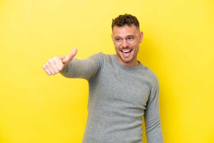 Foto jonge blanke knappe man geïsoleerd op gele achtergrond met een duim omhoog gebaar