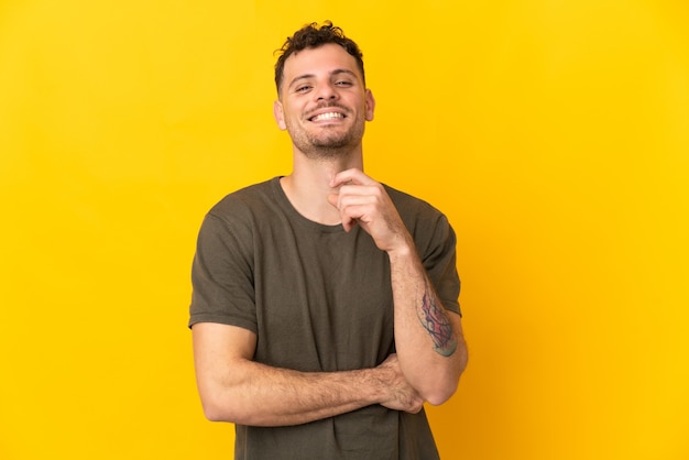 Jonge blanke knappe man geïsoleerd op gele muur lachen