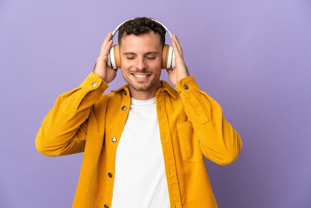 Jonge blanke knappe man geïsoleerd op paarse muziek luisteren