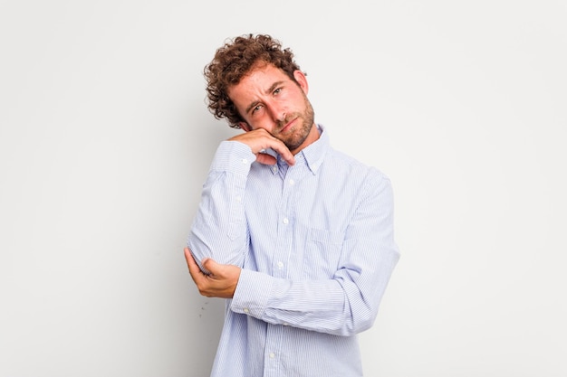 Jonge blanke, krullende man, geïsoleerd op een witte achtergrond, moe van een repetitieve taak.