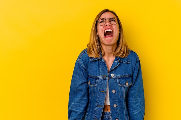 Jonge blanke magere vrouw geïsoleerd op gele achtergrond schreeuwen erg boos, gefrustreerd woedeconcept.