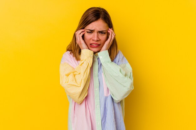 Jonge blanke magere vrouw geïsoleerd op gele muur huilen, ongelukkig met iets, pijn en verwarring concept.