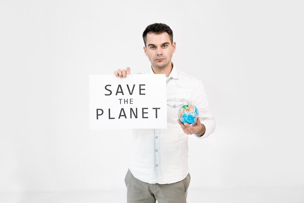 Jonge blanke man, beschermer van de wereld, vrijwilliger die zich op een witte achtergrond en aarde wereldbol en blad met de tekst van de planeet te houden.