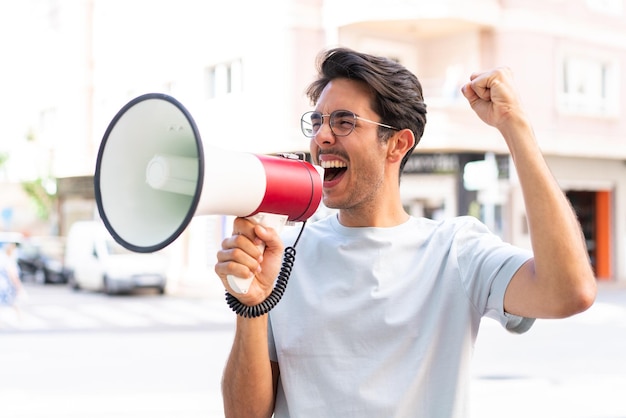 Jonge blanke man buiten die door een megafoon schreeuwt om iets in zijpositie aan te kondigen