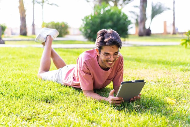 Jonge blanke man buiten in een park met een tablet