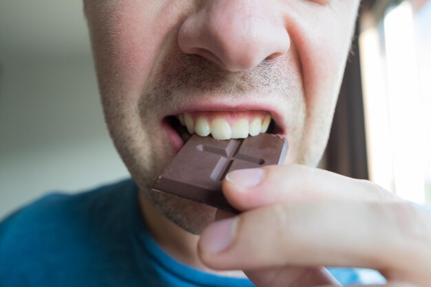 Jonge blanke man die alleen een chocolade eet