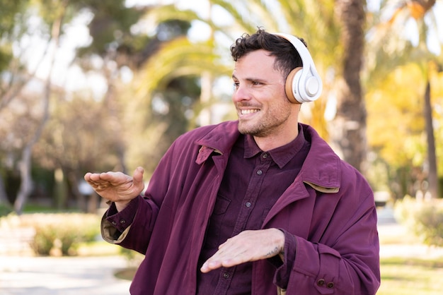 Jonge blanke man die buiten naar muziek luistert en danst