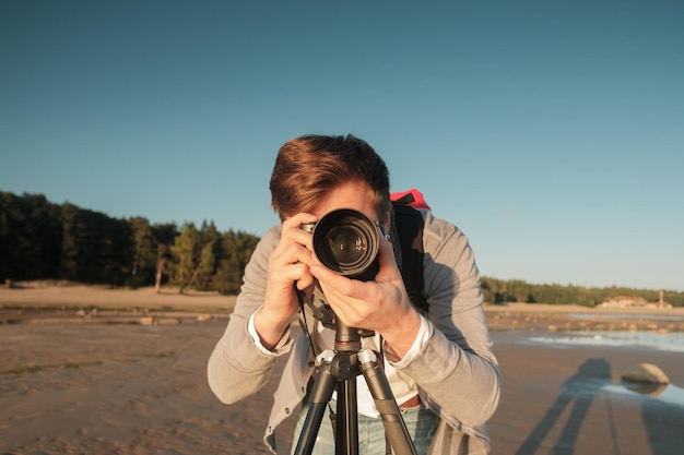 Jonge blanke man die foto maakt van landschap aan zee