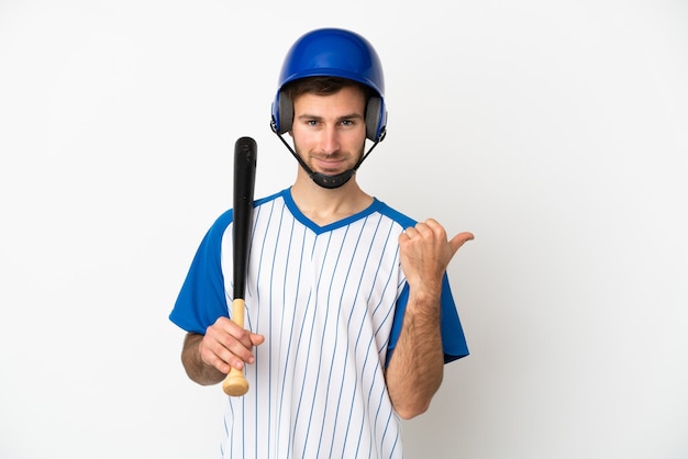 Jonge blanke man die honkbal speelt geïsoleerd op een witte achtergrond, wijzend naar de zijkant om een product te presenteren