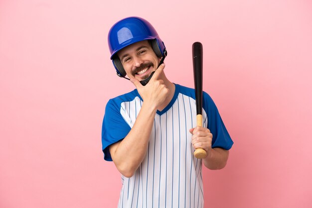 Jonge blanke man die honkbal speelt geïsoleerd op roze achtergrond gelukkig en glimlachend