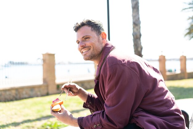 Jonge blanke man die sashimi eet in de open lucht