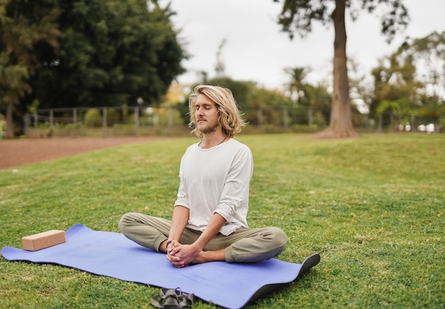 Jonge blanke man doet yoga-oefening in het stadspark - balans tussen werk en privé