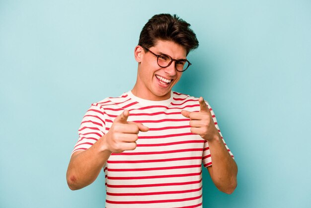 Jonge blanke man geïsoleerd op blauwe achtergrond wijzend naar voren met vingers
