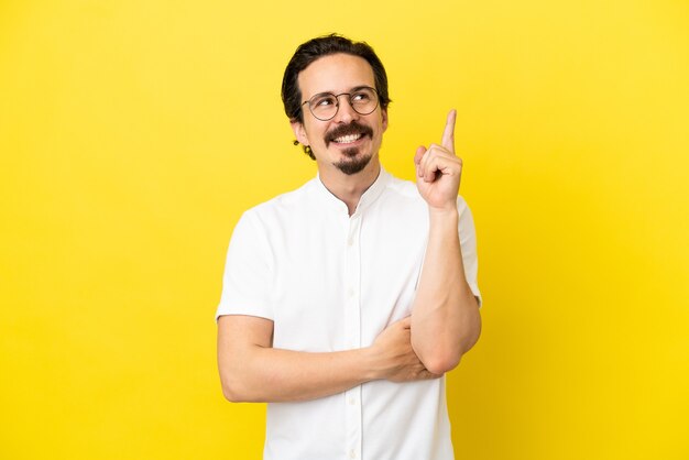 Jonge blanke man geïsoleerd op een gele achtergrond die een geweldig idee benadrukt