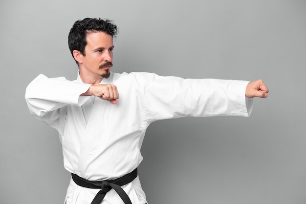 Jonge blanke man geïsoleerd op een grijze achtergrond karate