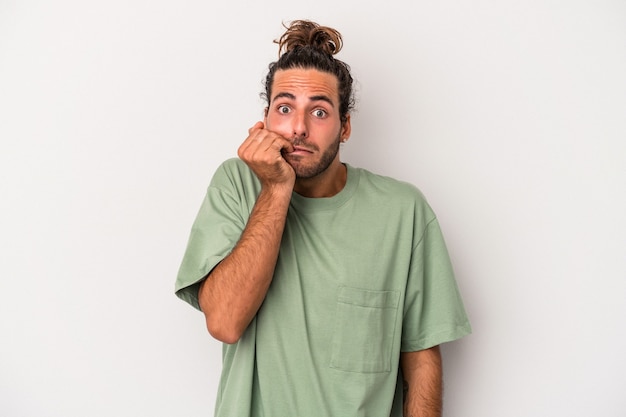 Jonge blanke man geïsoleerd op een grijze achtergrond vingernagels bijten, nerveus en erg angstig.