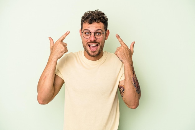 Jonge blanke man geïsoleerd op een groene achtergrond met een teleurstelling gebaar met wijsvinger.