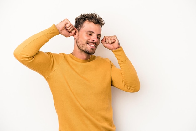 Jonge blanke man geïsoleerd op een witte achtergrond die een speciale dag viert, springt en armen opheft met energie.