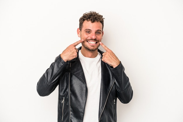 Jonge blanke man geïsoleerd op een witte achtergrond glimlacht, wijzende vingers naar de mond.