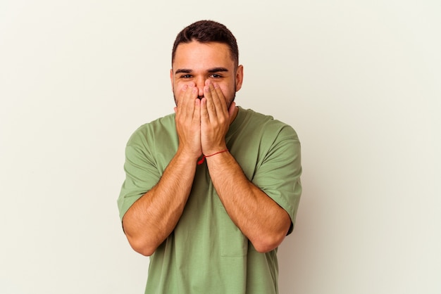 Jonge blanke man geïsoleerd op een witte achtergrond lachen om iets, mond bedekken met handen.