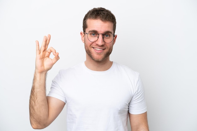 Jonge blanke man geïsoleerd op een witte achtergrond met een bril en doen ok sign