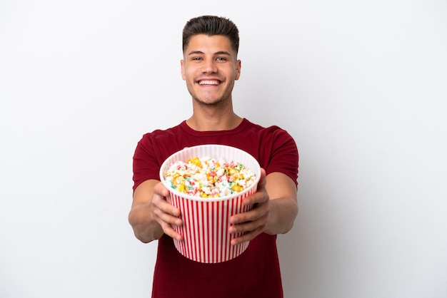 Jonge blanke man geïsoleerd op een witte achtergrond met een grote emmer popcorns