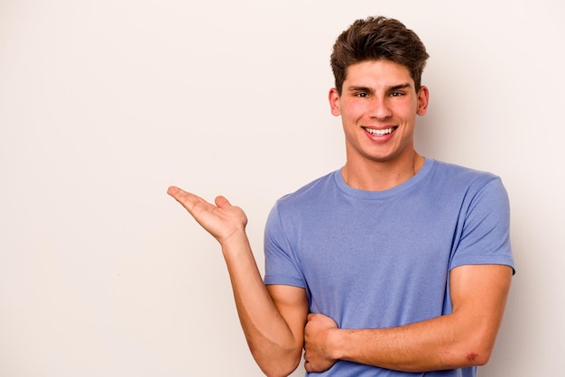 Jonge blanke man geïsoleerd op een witte achtergrond met een kopie ruimte op een handpalm en met een andere hand op de taille