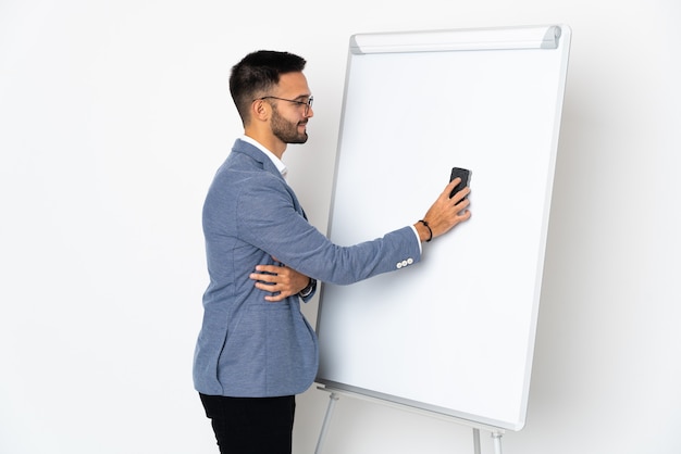 Jonge blanke man geïsoleerd op een witte achtergrond met een presentatie op wit bord