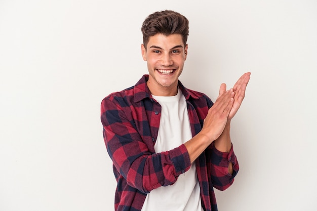 Jonge blanke man geïsoleerd op een witte achtergrond voelt zich energiek en comfortabel, wrijft zelfverzekerd over de handen.