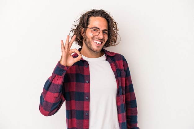 Jonge blanke man geïsoleerd op een witte achtergrond vrolijk en zelfverzekerd weergegeven: ok gebaar.