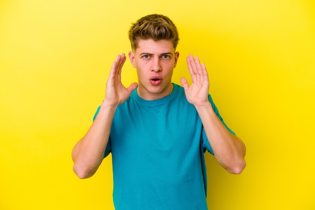 Jonge blanke man geïsoleerd op geel verrast en geschokt.