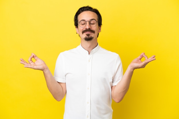 Jonge blanke man geïsoleerd op gele achtergrond in zen pose