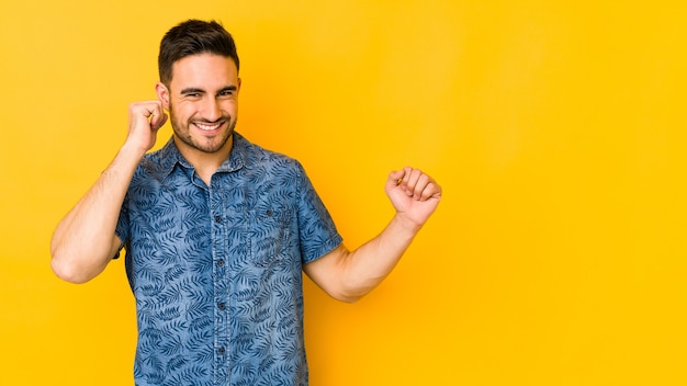 Jonge blanke man geïsoleerd op gele bakground dansen en plezier maken.